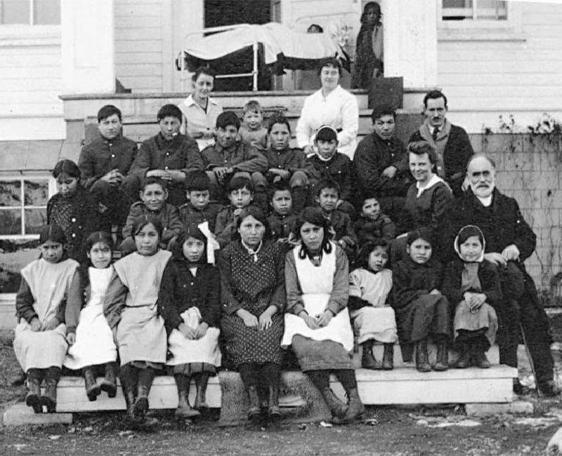 Group of people sitting in front of Sarcee St. Barnabas school