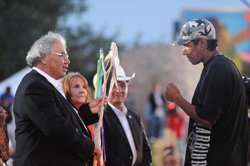 Justice Murray Sinclair speaks with an Indigenous man as others look on.