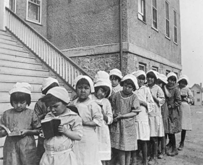 Children standing with books outside of Chapleau St. John's school