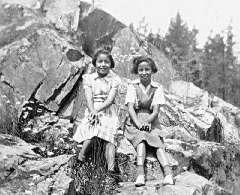 Two students sitting outside on rocks from Chapleau St. John's school