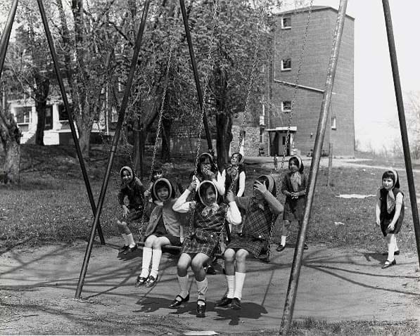 Children playing on swings by building at Mohawk Institute