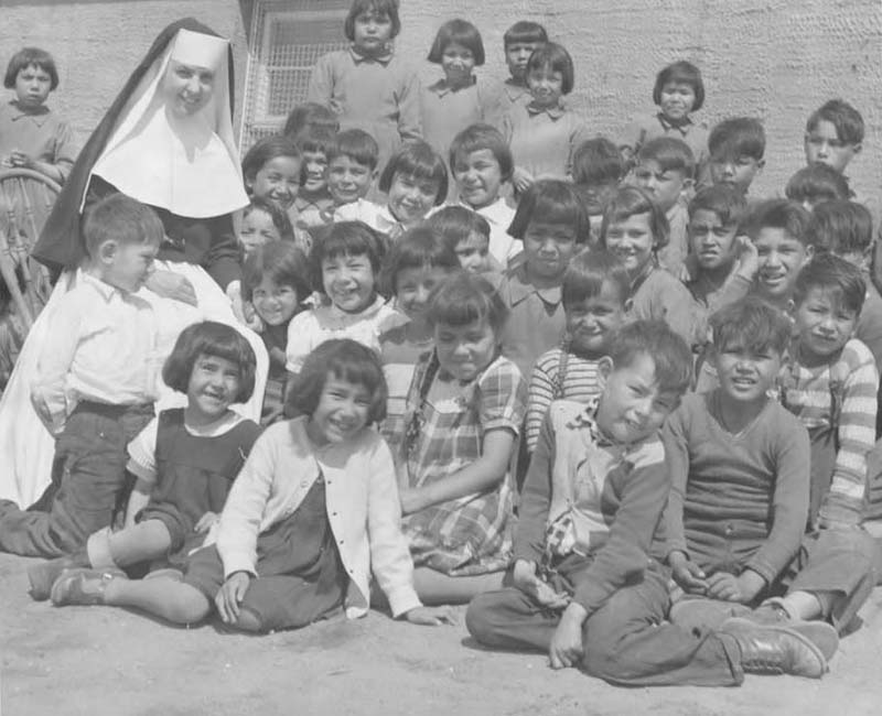 Group of students and nun posing for photo in front of Sept-Iles school