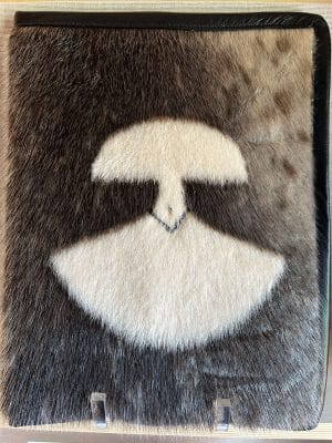 A publication titled "First Canadians, Canadians First: The National Strategy on Inuit Education" by ITK, housed in a distinctive black leather and sealskin folder featuring a "Kiluk, LTD" patch.