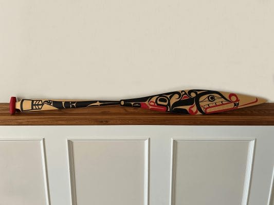 A ceremonial paddle carved by artist Carey Newman and painted by residential school Survivor Victor Newman, introduced in 2019 by the University of Victoria for the Building Reconciliation Forum.